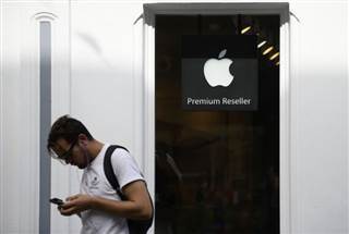 A man looks at his phone as he walks past an authorised apple reseller store in Galway