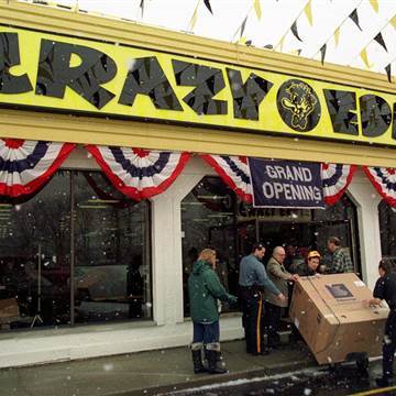 Image: Workers bring out a large-screen television at the grand opening of a new Crazy Eddie electronics store