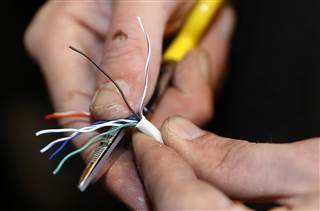 A technician strips back covering from a ethernet cable at a residential home as part of Google Fiber services in Provo