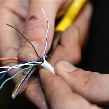 A technician strips back covering from a ethernet cable at a residential home as part of Google Fiber services in Provo