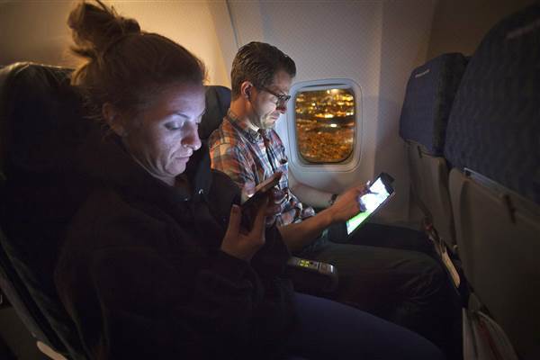 Image: People use their smart devices on an American Airlines airplane, which is equipped with Gogo Inflight Internet service, enroute from Miami to New York.