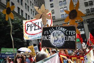 Image: Climate change activists carry signs as they march during a protest in downtown in Philadelphia a day before the start of the Democratic National Convention on July 24, 2016.