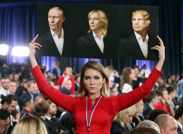 Image: A journalist holds a board with portraits of Putin, Le Pen, Trump