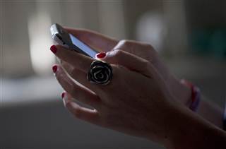 Image: A woman poses for a photo using her smart phone