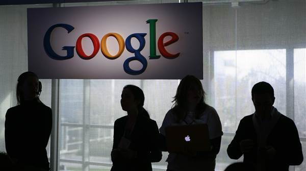 Image: People stand under a sign at Google headquarters