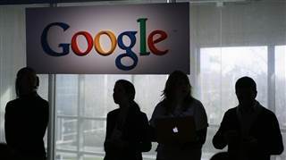 Image: People stand under a sign at Google headquarters