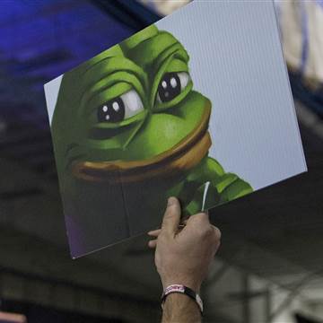 Image: An attendee holds up a sign of Pepe the Frog, a cartoon tied to anti-Semitism and racism that has become an unofficial mascot of the alt-right, during a campaign event with Donald Trump at a sports complex in Bedford, N.H.