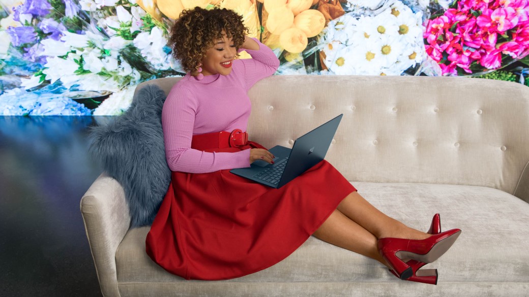 A woman working on her surface laptop on the couch