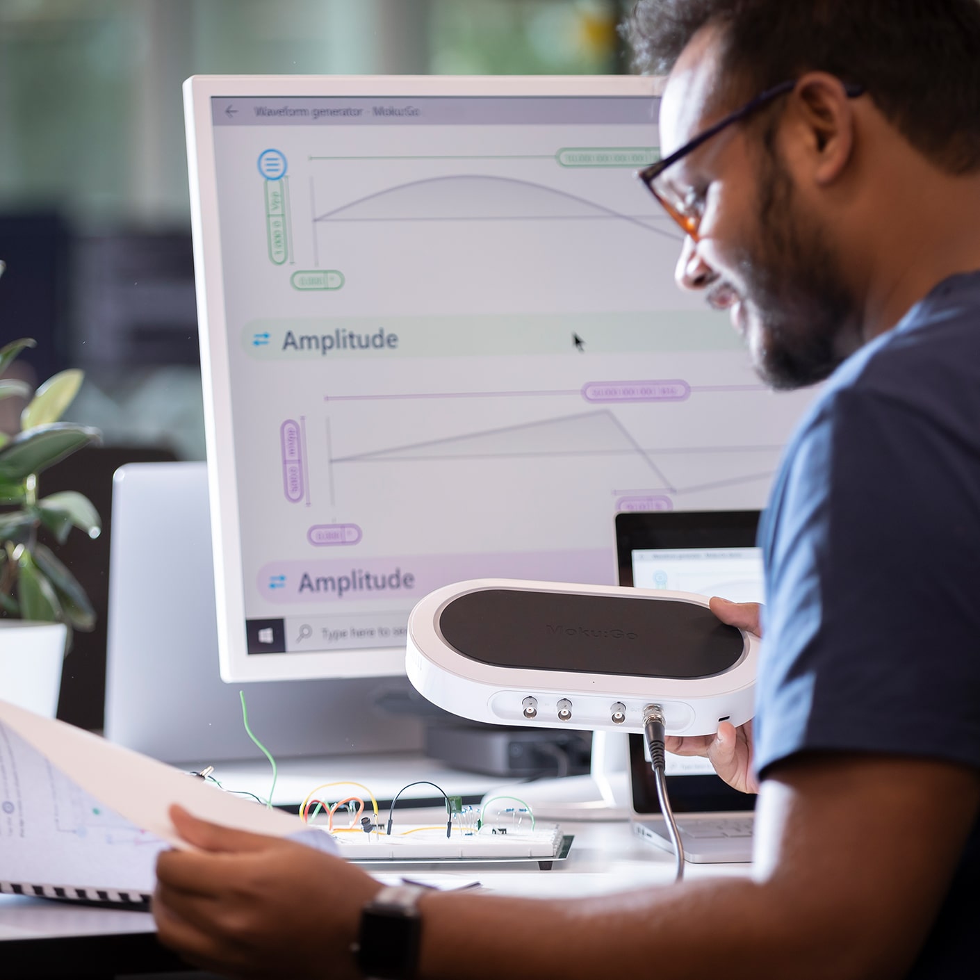 A person uses a Moku Go device at a desk.