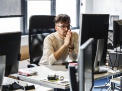 Microsoft provides code evaluation to .NET Upgrade Assistant Programmer sitting at the desk in his office and trying to solve problem of new code.