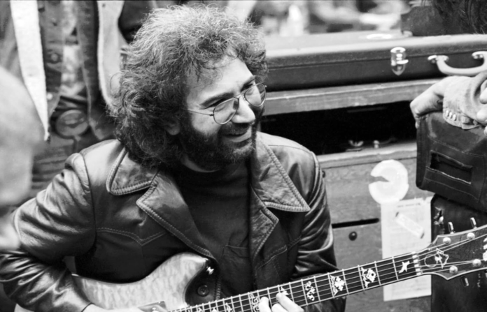 A black-and-white photo of Jerry Garcia playing guitar.