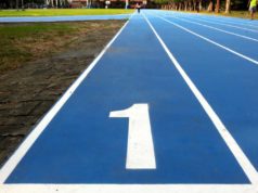 Uno Platform unveils visible designer for cross-platform… Number 1 / number one lane of running track, white number and white lane lines on blue surface. Low level view with grass runners trees visible in the distance.
