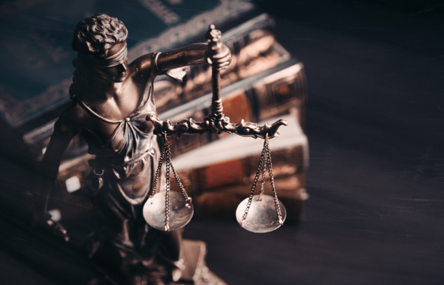 Statue of the Lady Justice with lawbooks on the background.