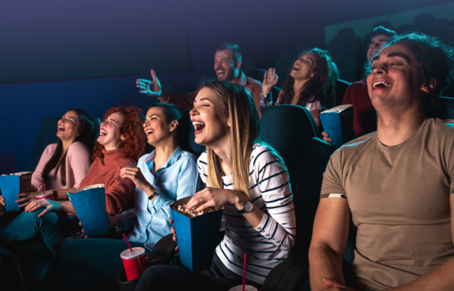 Group of people laughing while watching a movie.