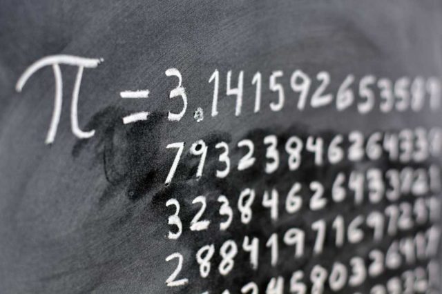 The number pi = 3.1415926 etc. written out to several lines of digits with white chalk on a blackboard. Slightly angled view.