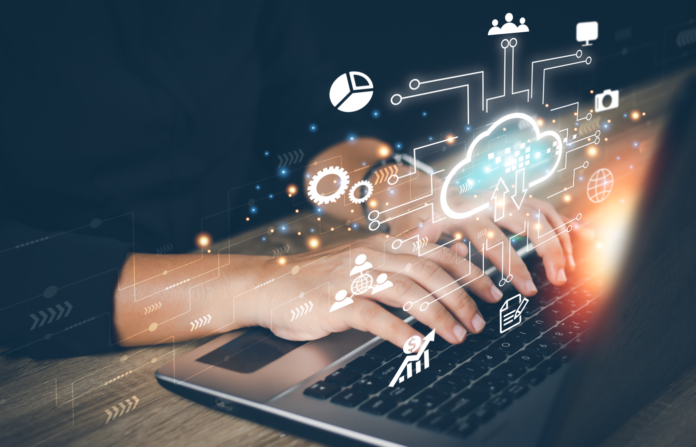 Businesswoman using laptop to access cloud computing system with various cloud-related images on virtual screen.