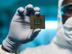 AI Chip Export Sanctions: Protecting or Impeding Growth? Man in protective suit and gloves holding a processing chip.