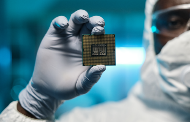 Man in protective suit and gloves holding a processing chip.