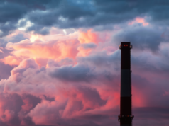 Artificial Intelligence Boom To Cause Thousands Of Deaths, $… Industrial chimney stack silhouette against a cloudy sky background.