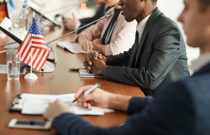 Government hearing session with the US flag on the table.