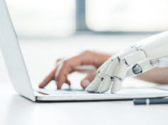 AI Companions Are ‘More Addictive Than Social Media,’ Expert… A human hand and a robotic hand operating a laptop.