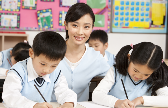1741887829_China’s-AI-Education-Starts-at-Age-6-—-Is-the.png Teacher assisting students in class.