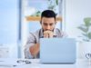 Excited or Concerned About AI? Find Out How Answers By Exper… Stock image of a worker who appears to be stressed looking at his laptop.