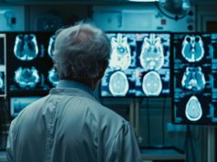 AI Helps Radiologists Save Lives When Every Second Counts A doctor in a white lab coat examines X-ray images on multiple monitors in a dimly lit medical facility, focusing on the detailed scans.