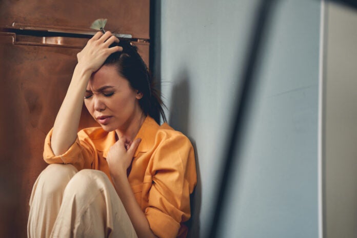Unhappy young lady sitting on the floor at home.