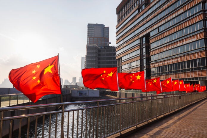 Row of Chinese flags on Huangpu river promenade, Shanghai, China.