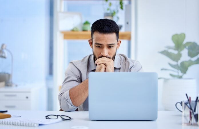 Stock image of a worker who appears to be stressed looking at his laptop.