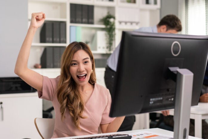 Female employee raising hands happy and laugh for receiving good news.