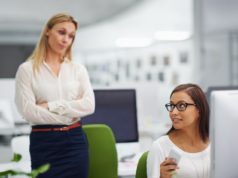 AI Adoption Barrier That Managers Might Overlook, Says Duke … Stock photo of two workers in an office with one person appearing to look at the other with judgment.