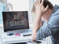 Anthropic CEO: AI Will Soon Take Nearly Half of Entry-Level … Man holds head with hands on table with laptop. Looking for remote work.