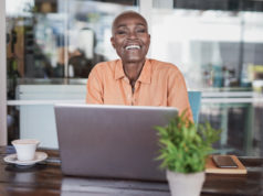 Emotional AI? Claude Makes Users Feel Better Woman sitting in a bar outdoor and working with laptop.