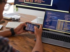 SmartBear unveils AI-driven take a look at automation for iOS and… A developer / programmer reviews code on mobile phone, laptop, and desktop displays.