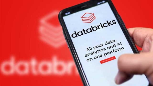 Databricks-at-a-crossroads-Can-its-AI-strategy-prevail.jpg A photograph of a Databricks website on a phone being held in front of a larger, blurry version of the Databricks logo.