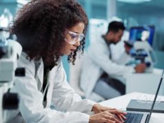 Designing AI-ready architectures in compliance-heavy… Scientist, woman and microscope with computer for laboratory research, test and DNA investigation at night. Professional doctor or science expert with lens check, laptop and particles for inspection