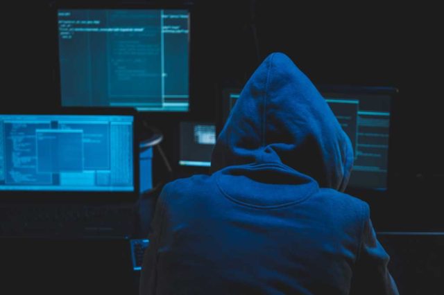 NPM-attacks-and-the-security-of-software-supply-chains.jpg Hacker using computer for organizing massive data breach attack on goverment servers. Hacker in dark room surrounded computers