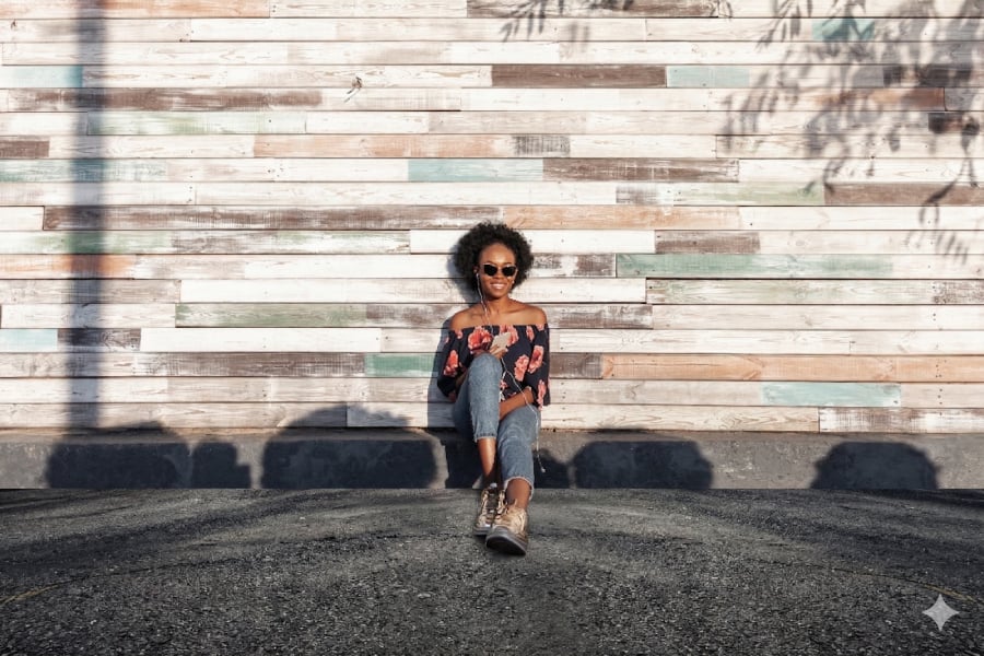 Image result of a woman smiling outside as she sits in the pavement listening to music.