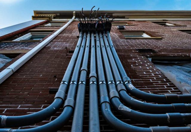 Electrical conduits running down the side of a building.