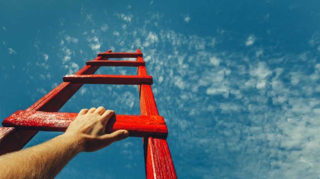 The-strangest-developer-productivity-metric-of-all-time.jpg Development Attainment Motivation Career Growth Concept. Mans Hand Reaching For Red Ladder Leading To A Blue Sky